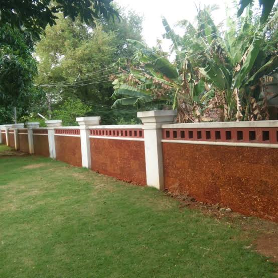 Laterite stone compound wall with white pillars