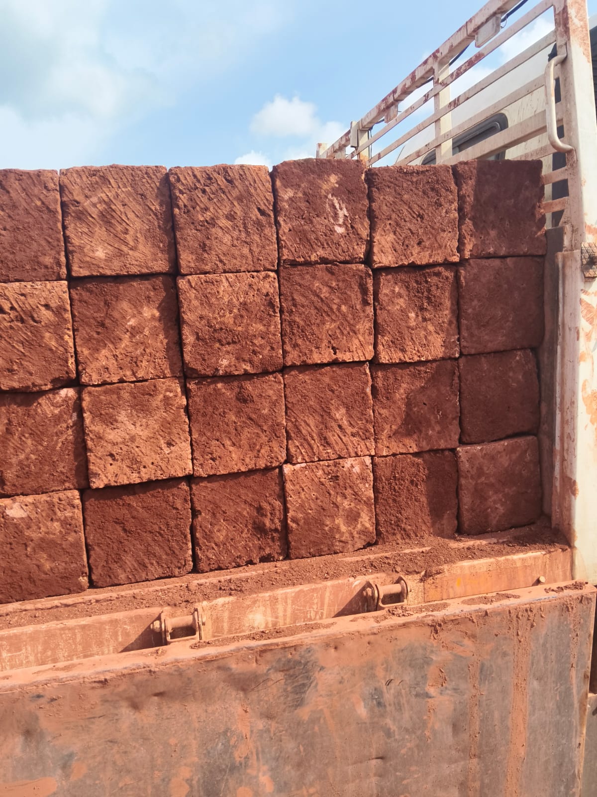 Laterite stone blocks stacked on lorry against a blue sky