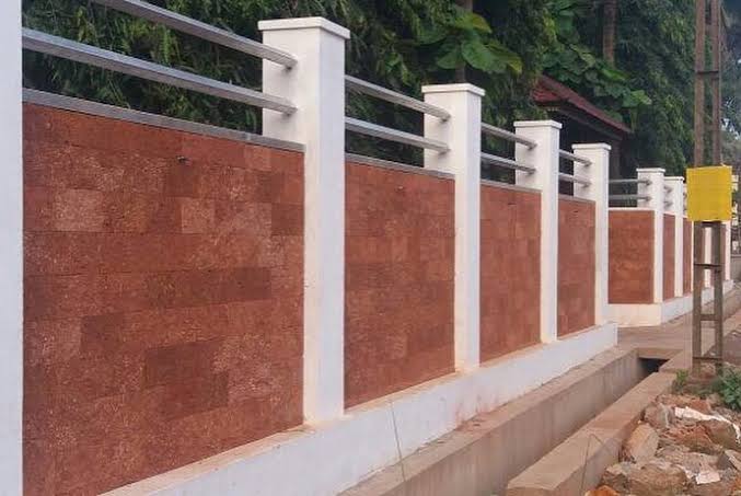 Laterite boundary wall with metal rails